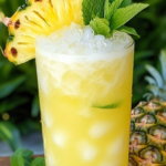 Pineapple Lime Breeze Cocktail served over ice with fresh pineapple chunks and lime slices in a tall glass.