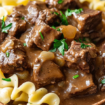 Tender Crockpot Beef Tips and Noodles served with rich gravy over egg noodles, garnished with parsley.