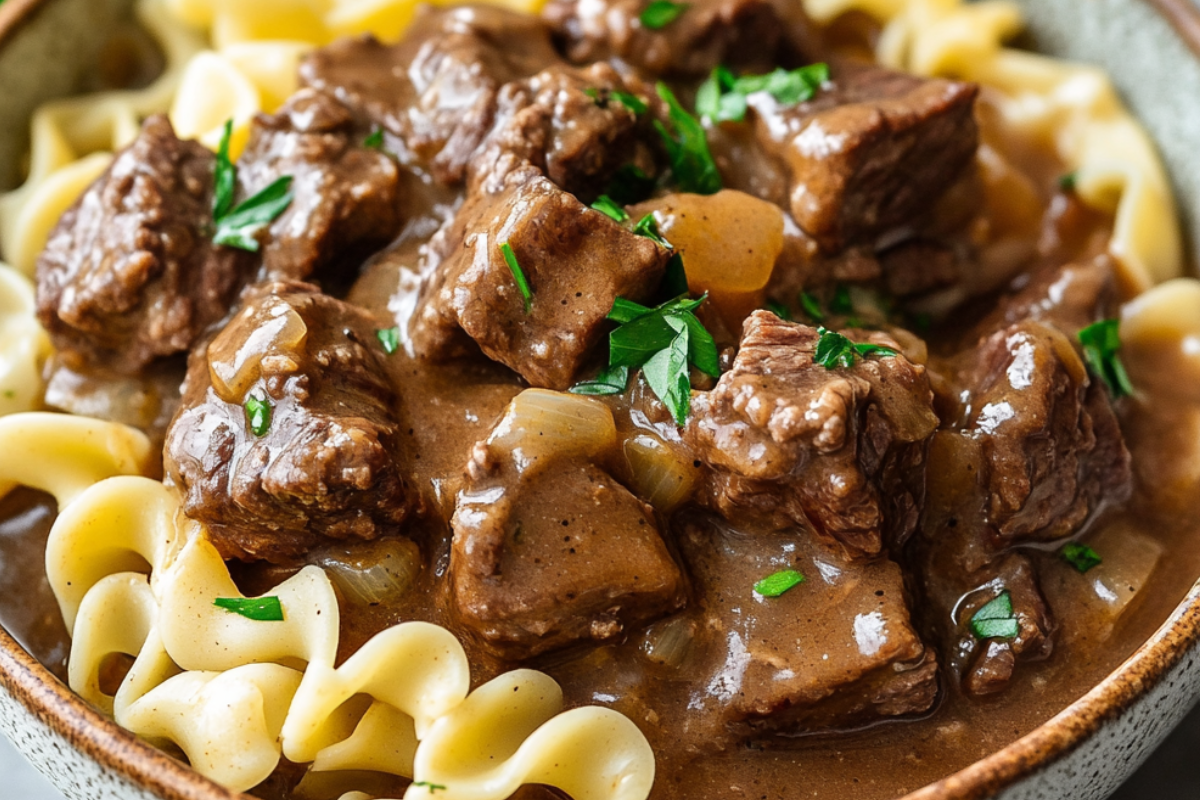 Tender Crockpot Beef Tips and Noodles served with rich gravy over egg noodles, garnished with parsley.