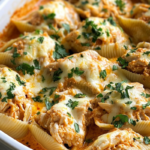 Creamy Cajun Chicken Stuffed Shells baked with cheese and spicy Alfredo sauce, served hot in a casserole dish